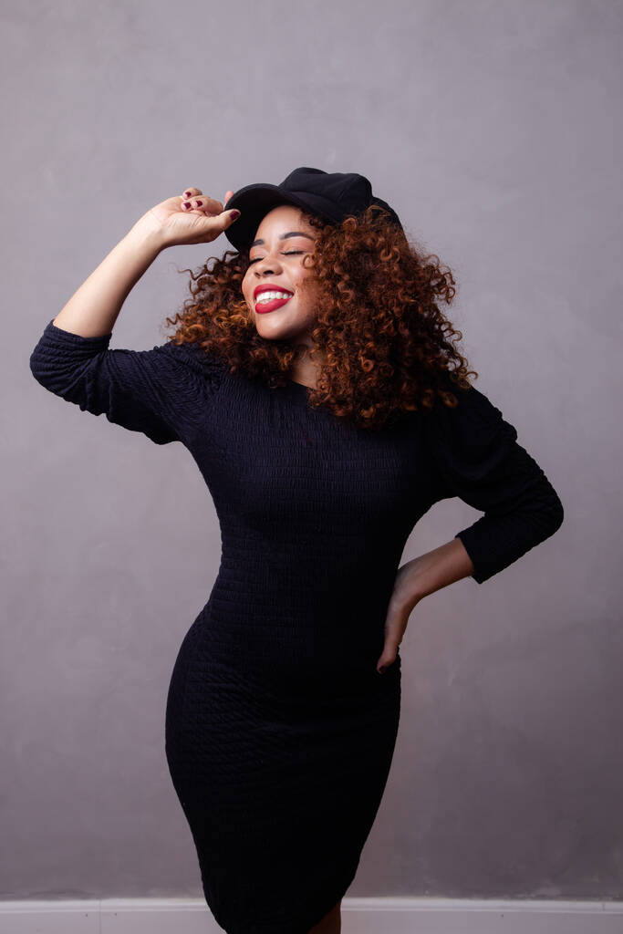 Afro nainen kihara tukka yllään baskeri ja lämpimät vaatteet. - Valokuva, kuva