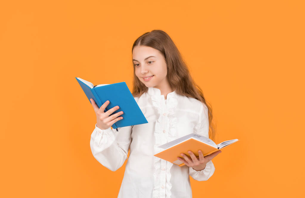 fröhliches Kind liest Schulbuch auf gelbem Hintergrund, Schule. - Foto, Bild
