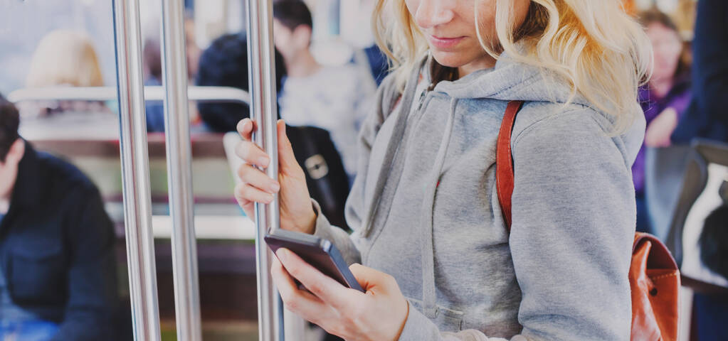 Person schaut auf den Bildschirm des Smartphones in der U-Bahn, Frau hält Handy in der U-Bahn - Foto, Bild