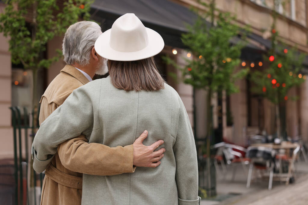 Ласковая пожилая пара, гуляющая на улице, вид сзади. Пространство для текста - Фото, изображение