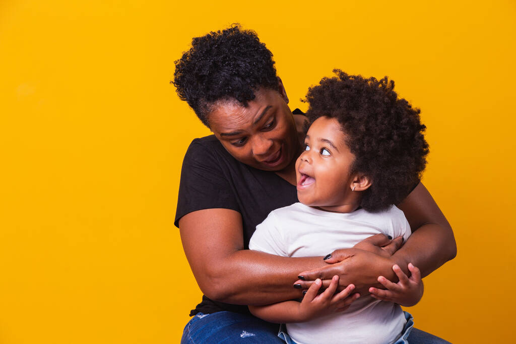 Feliz Dia da Mãe! Adorável doce mãe afro-americana com filhinha fofa. Mãe mais velha com sua filha no fundo amarelo. - Foto, Imagem