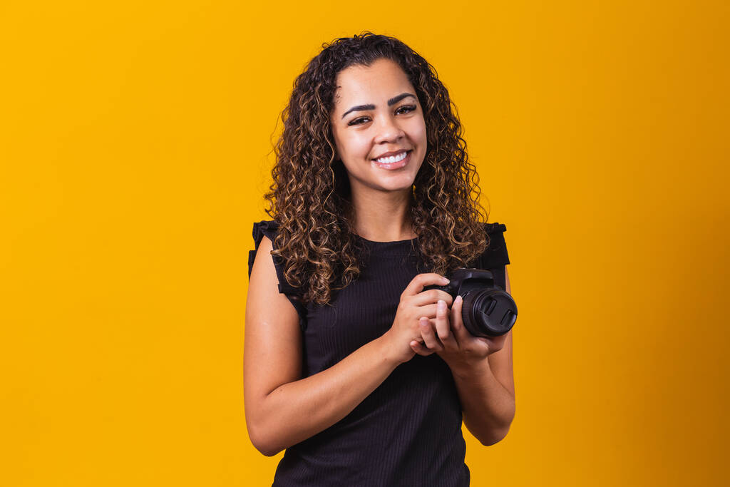 Mladý afro žena fotografie na žlutém pozadí drží fotoaparát. - Fotografie, Obrázek