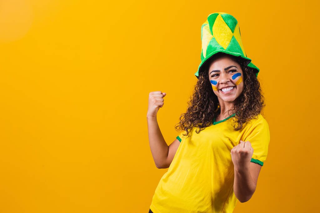 Apoyador brasileño. Aficionada brasileña celebrando en el fútbol o partido de fútbol sobre fondo amarillo. Colores de Brasil. Sí.! - Foto, Imagen
