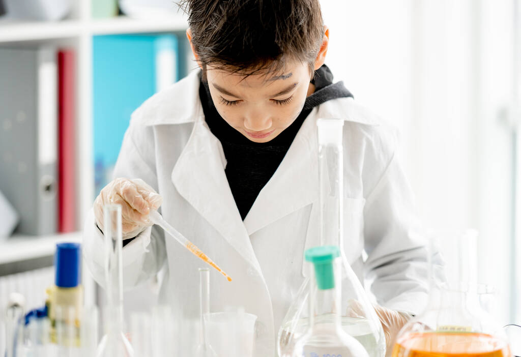 Školák provádějící chemický experiment na měření chemických kapalin v základní vědecké třídě. Chytré výsledky analýzy žáků v laboratoři - Fotografie, Obrázek