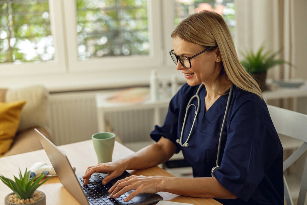 Médico viendo webinar médico en línea mientras está sentado con el ordenador portátil en la oficina - Foto, imagen