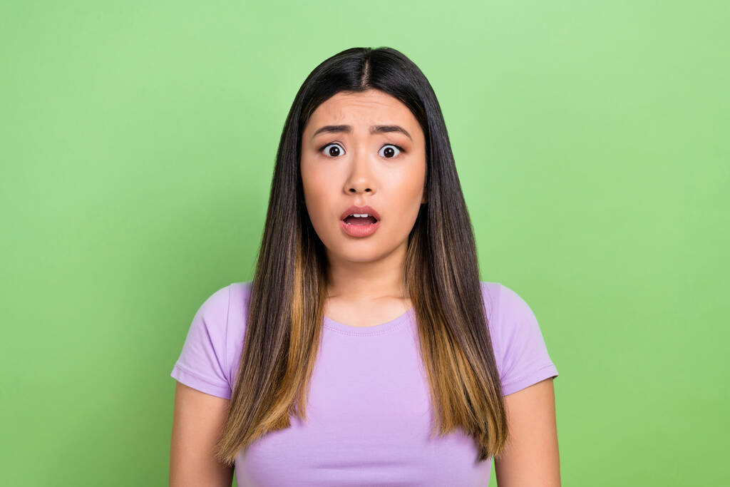 Foto de retrato de mujer joven japonesa usar púrpura elegante camiseta confundida mirando el pelo marrón asustado aislado en el fondo de color verde. - Foto, Imagen