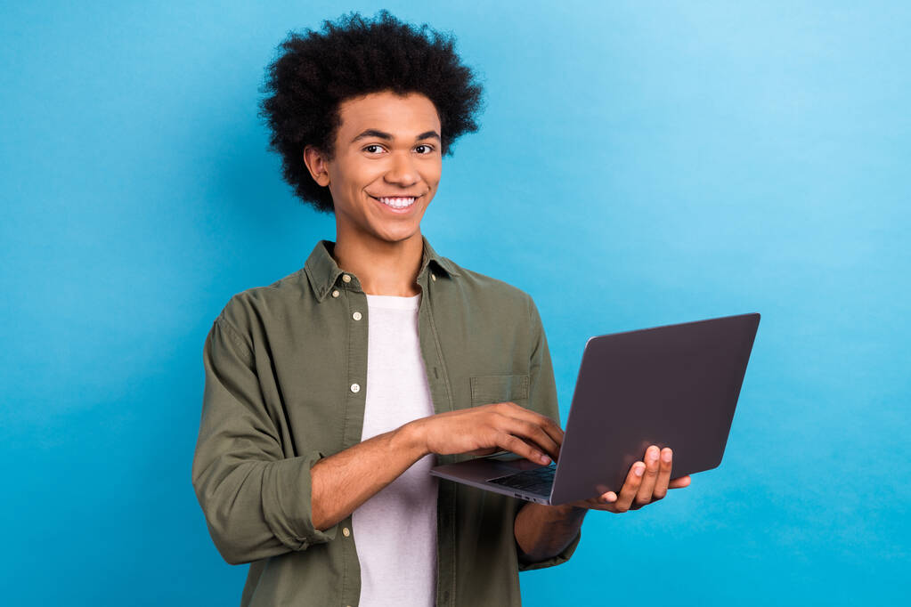 Portret pozytywnej osoby ząb uśmiech trzymać używać bezprzewodowego netbook izolowane na tle niebieskiego koloru. - Zdjęcie, obraz