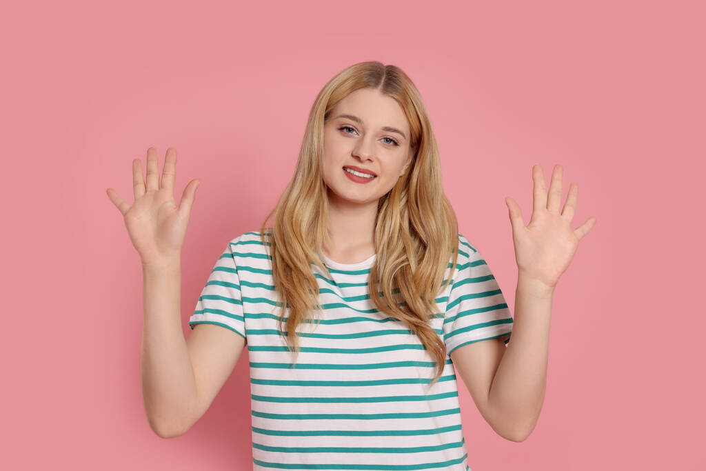 Mujer feliz dando cinco alto con ambas manos sobre fondo rosa - Foto, imagen