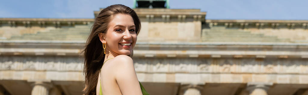 Mosolygó nő a kamerába néz, miközben a Brandenburg kapu közelében áll Berlinben, Németországban, banner  - Fotó, kép