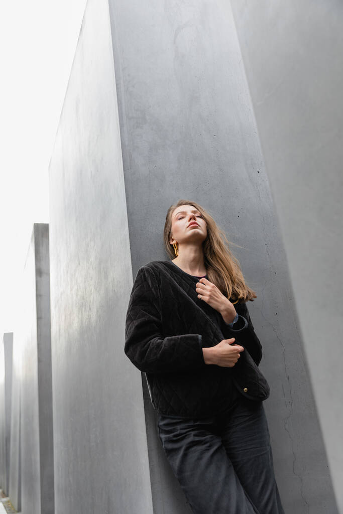 Jonge blonde vrouw in jasje tussen Memorial to Murdered joden of Europe in Berlijn - Foto, afbeelding