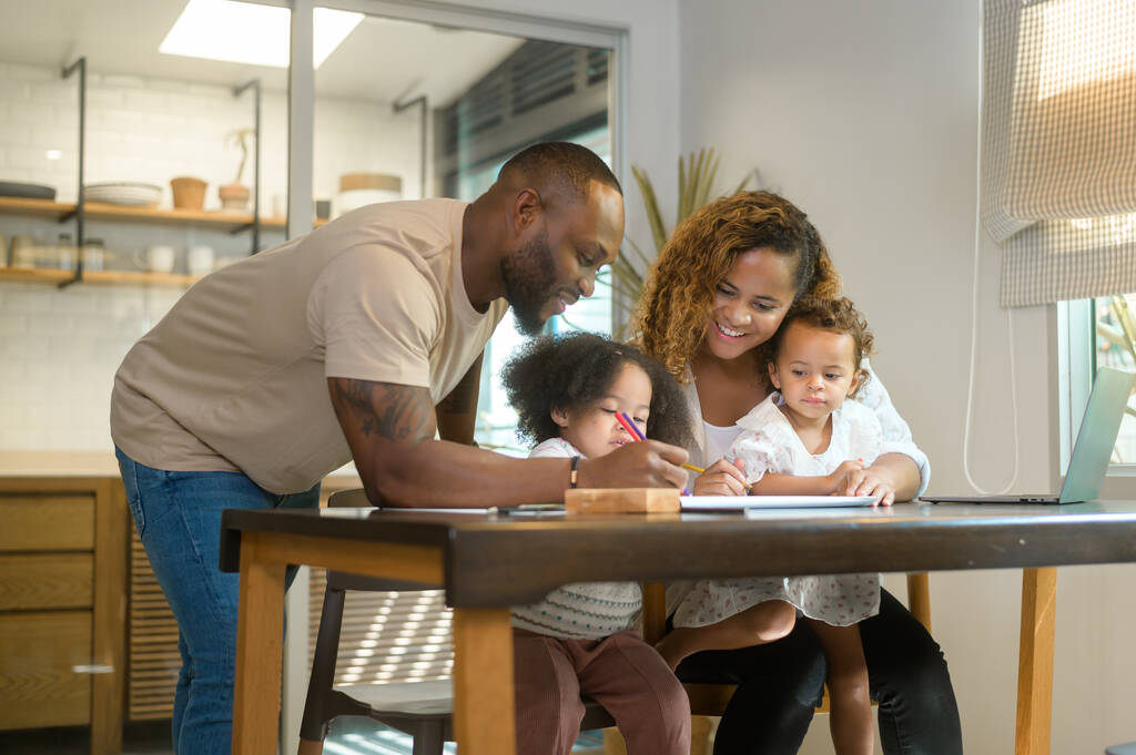 Feliz padre afroamericano jugando y dibujando con hijas en casa  - Foto, Imagen