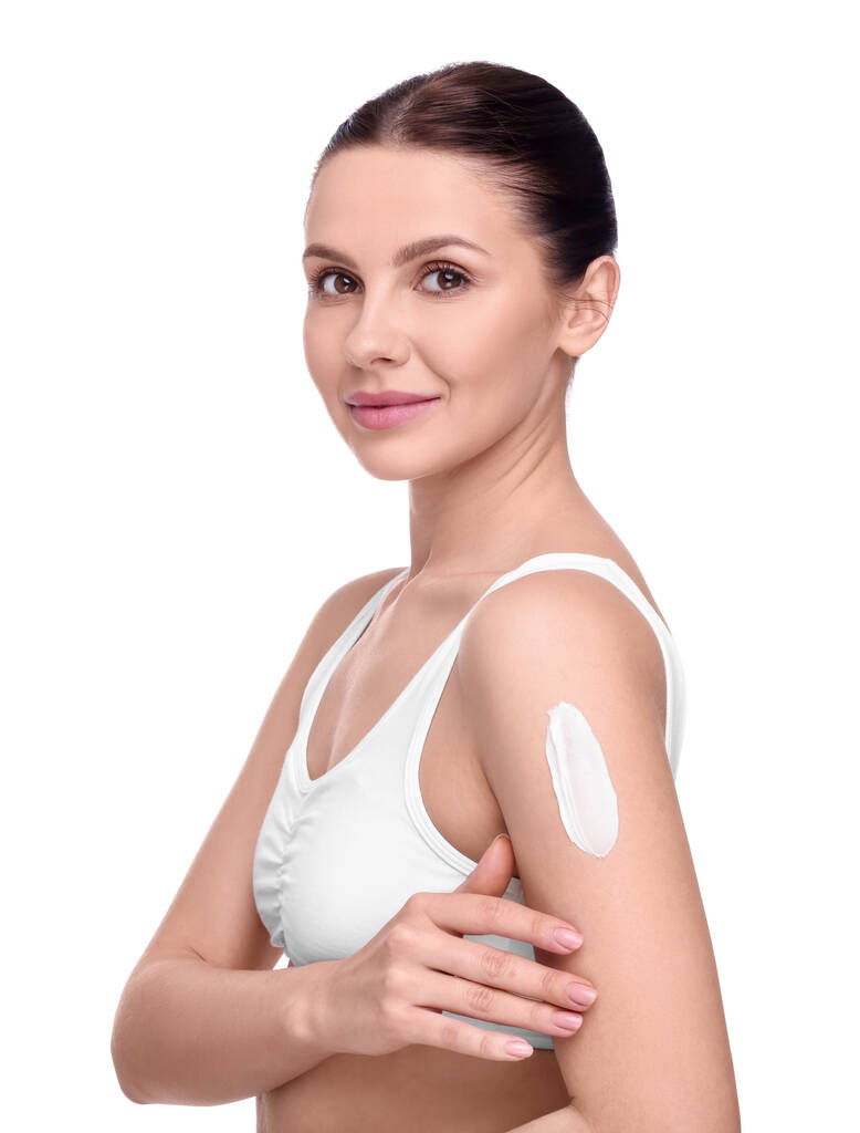 Mooie vrouw met uitstrijkje van body cream op haar arm tegen witte achtergrond - Foto, afbeelding
