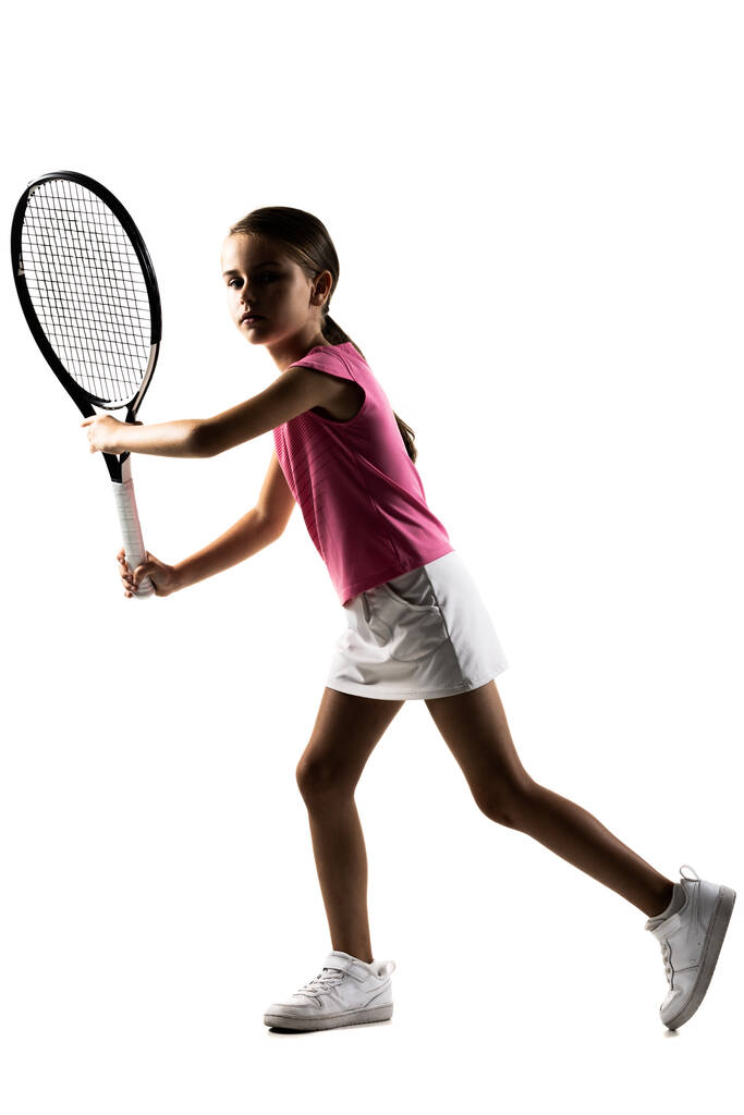 Młoda tenisistka w różowym stroju. Mała dziewczynka pozująca z rakietą i piłką. Połowa sylwetki izolowana na białym tle. - Zdjęcie, obraz