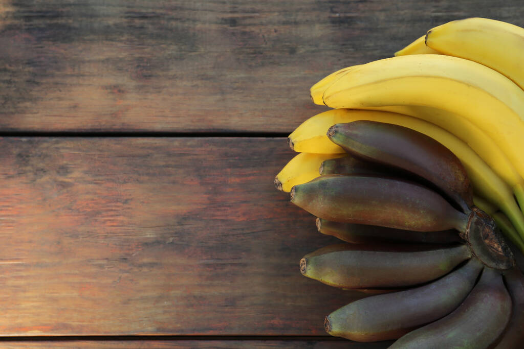 Diversi tipi di banane sul tavolo in legno, vista dall'alto. Spazio per testo - Foto, immagini