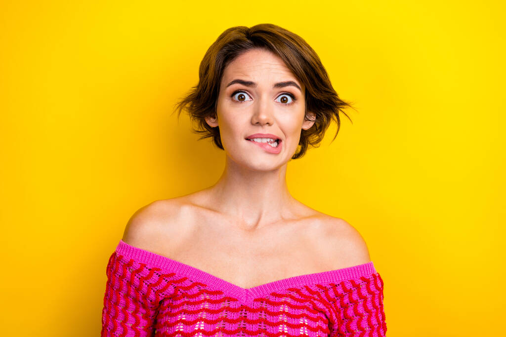 Portrait of impressed frightened pretty woman with short haircut wear pink dress biting lips staring isolated on yellow color background. - Photo, Image