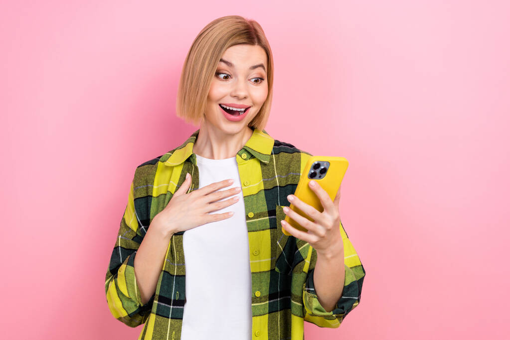 Ritratto di stupefatto divertente signora mano touch petto uso smart phone isolato su sfondo di colore rosa. - Foto, immagini
