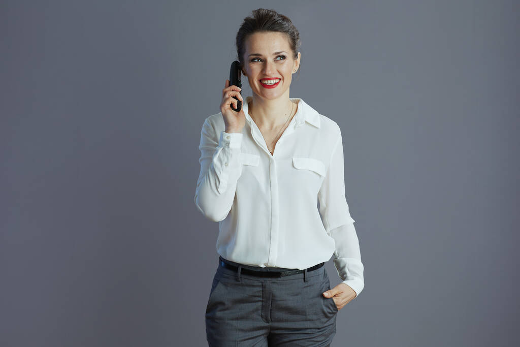sorrindo mulher elegante trabalhador em blusa branca falando no telefone de rádio velho isolado em cinza. - Foto, Imagem
