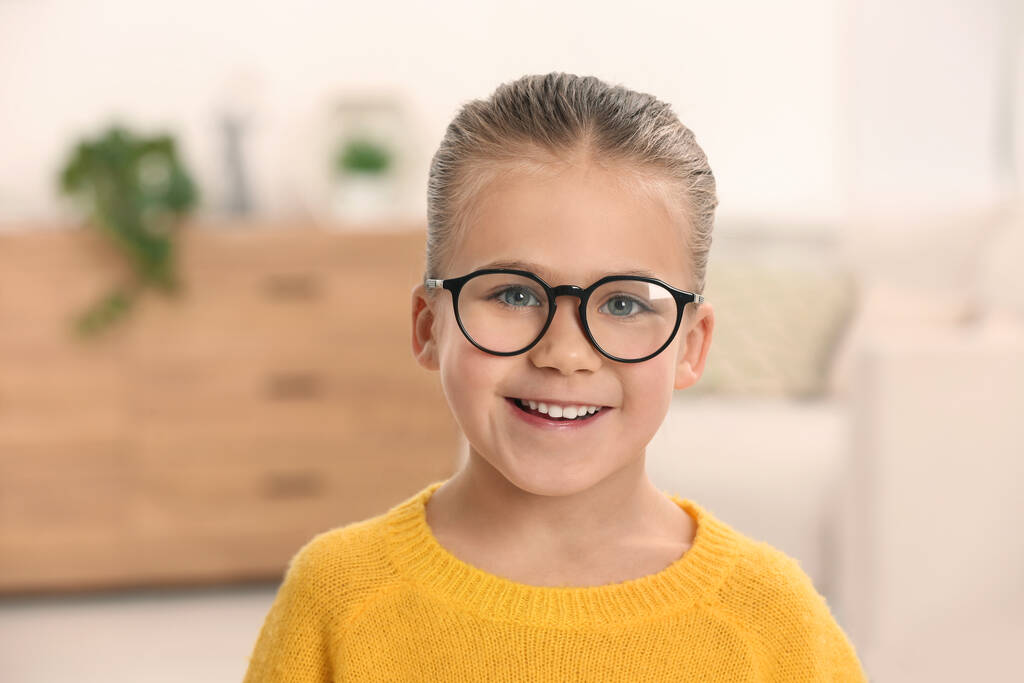 Portret van een schattig meisje met een bril binnen - Foto, afbeelding