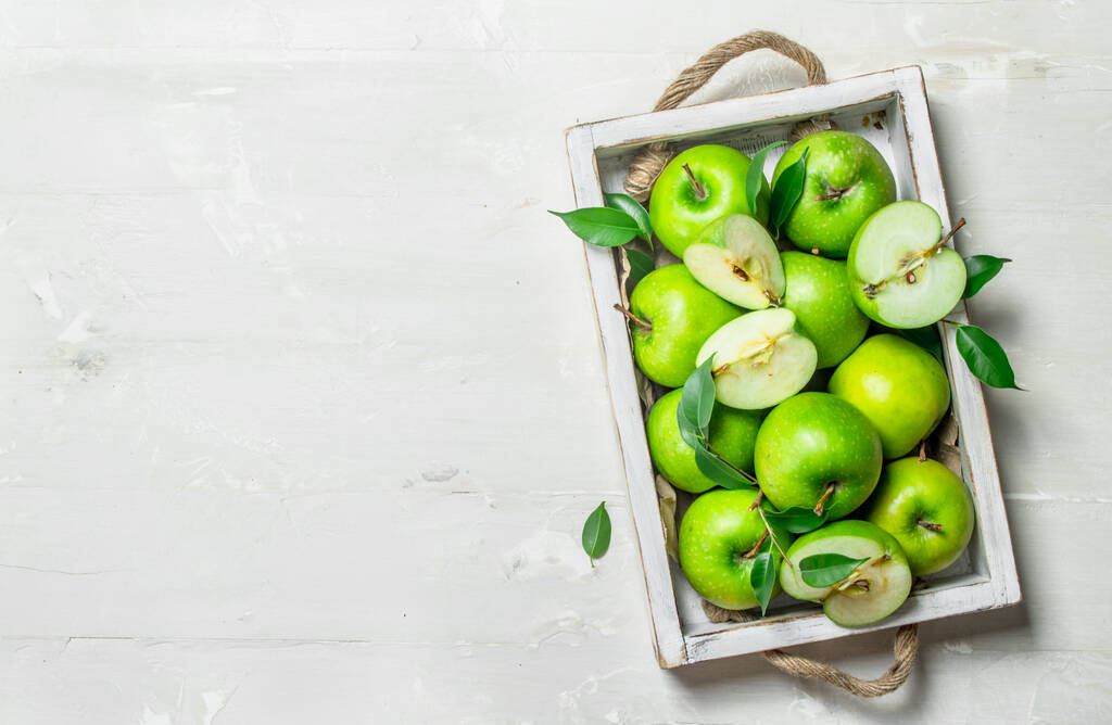 Zöld alma egy fa tálca. Fehér rusztikus háttér . - Fotó, kép