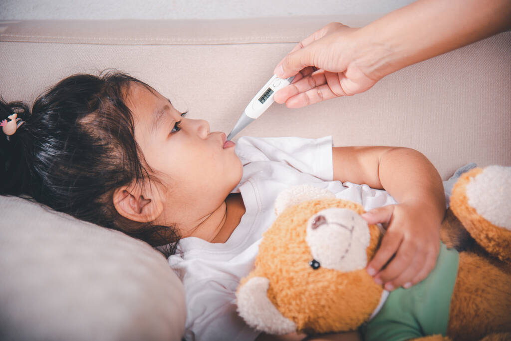 Хвора дитина. Мати-батько перевіряє температуру своєї хворої дочки з цифровим термометром у роті, дитина лежить у ліжку, вимірюючи її температуру за гарячкою та хворобою, охорона здоров'я
 - Фото, зображення