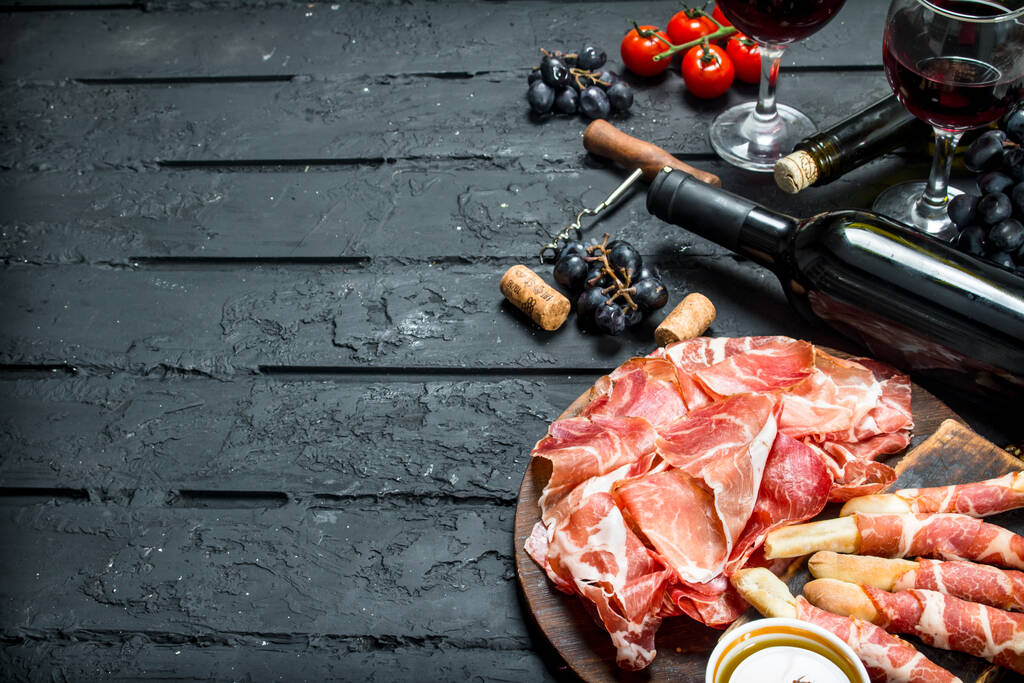 Fondo antipasto. Aperitivos italianos tradicionales con vino tinto. Sobre fondo rústico negro
. - Foto, Imagen
