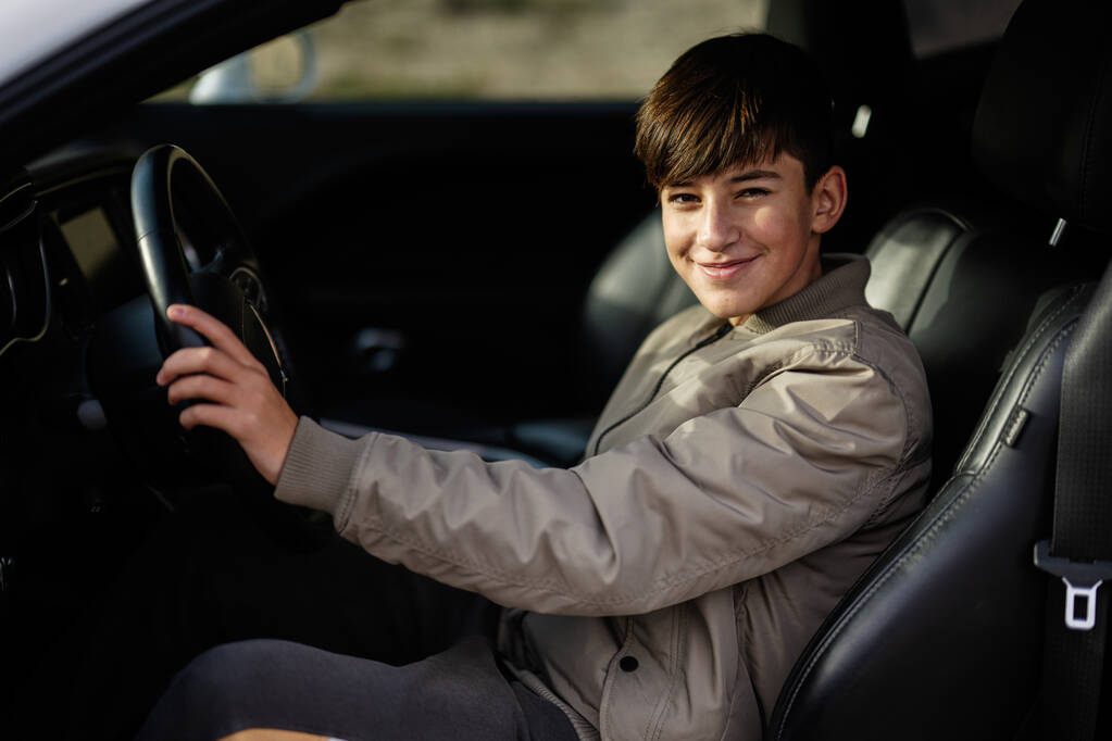 Хлопчик-підліток сидить у м'язовій машині. Молодий підліток водій
. - Фото, зображення