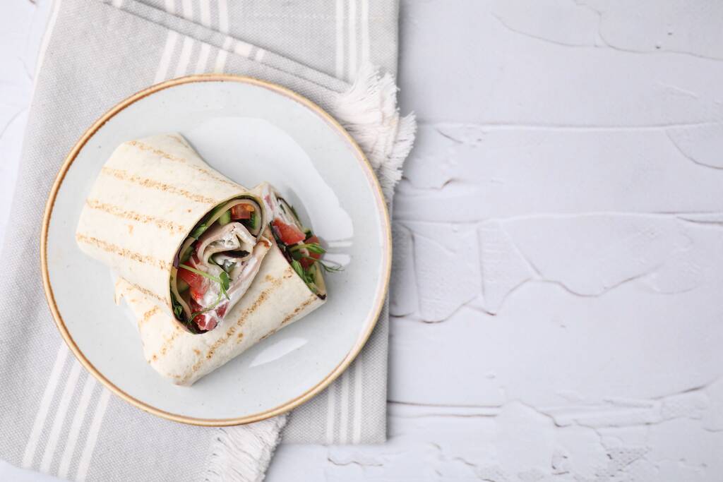 Deliciosos envoltórios sanduíche com legumes frescos na mesa texturizada branca, vista superior. Espaço para texto - Foto, Imagem