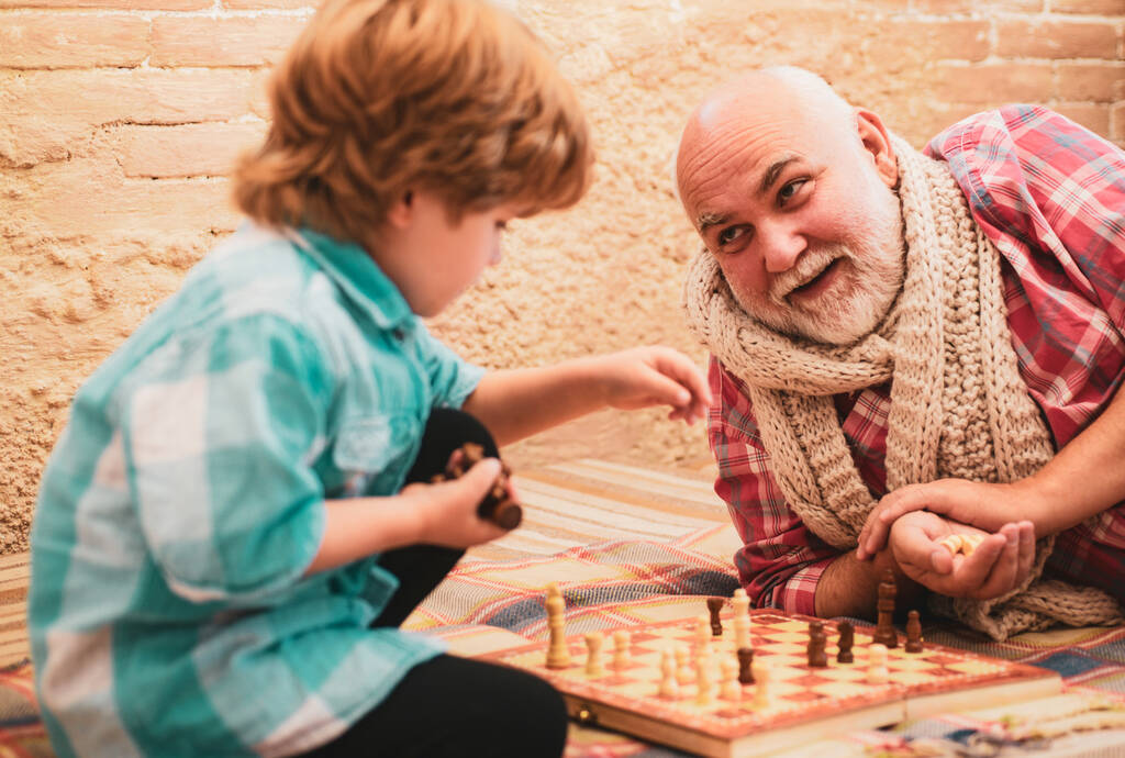 Büyükbaba torunuyla satranç oynuyor. Büyükbabam ve torunum satranç oynuyorlar. Satranç stratejisi geliştiren sevimli çocuk. - Fotoğraf, Görsel