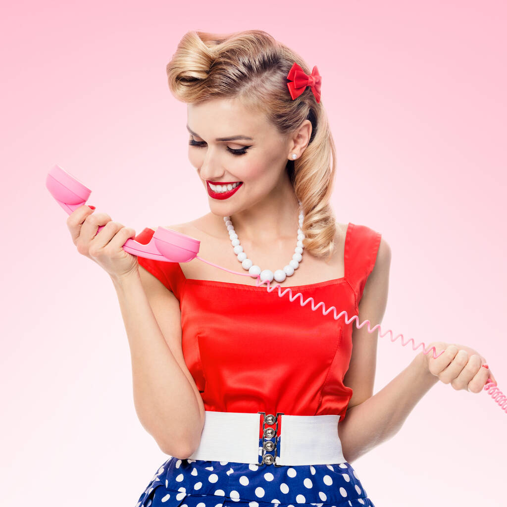 Hauska muotokuva kaunis nainen puhelin pukeutunut pin-up tyyli mekko pilkku, vaaleanpunainen tausta. Valkoihoinen vaalea malli poseeraa retro muoti ja vintage konsepti studio ampua. - Valokuva, kuva