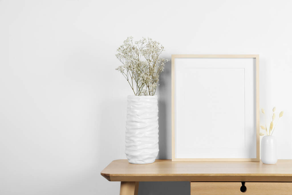 Prázdný fotografický rámeček, vázy se suchými ozdobnými hroty a gypsophila květinami na dřevěném stole. Mockup pro design - Fotografie, Obrázek