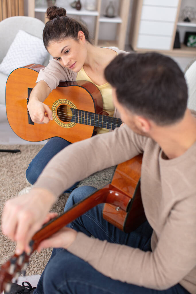 Ένας άντρας παίζει κιθάρα για μια όμορφη γυναίκα. - Φωτογραφία, εικόνα