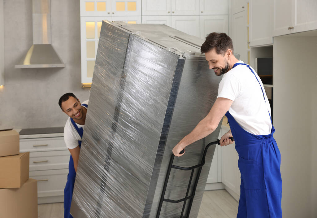 Traslochi maschili che trasportano frigorifero in una nuova casa - Foto, immagini