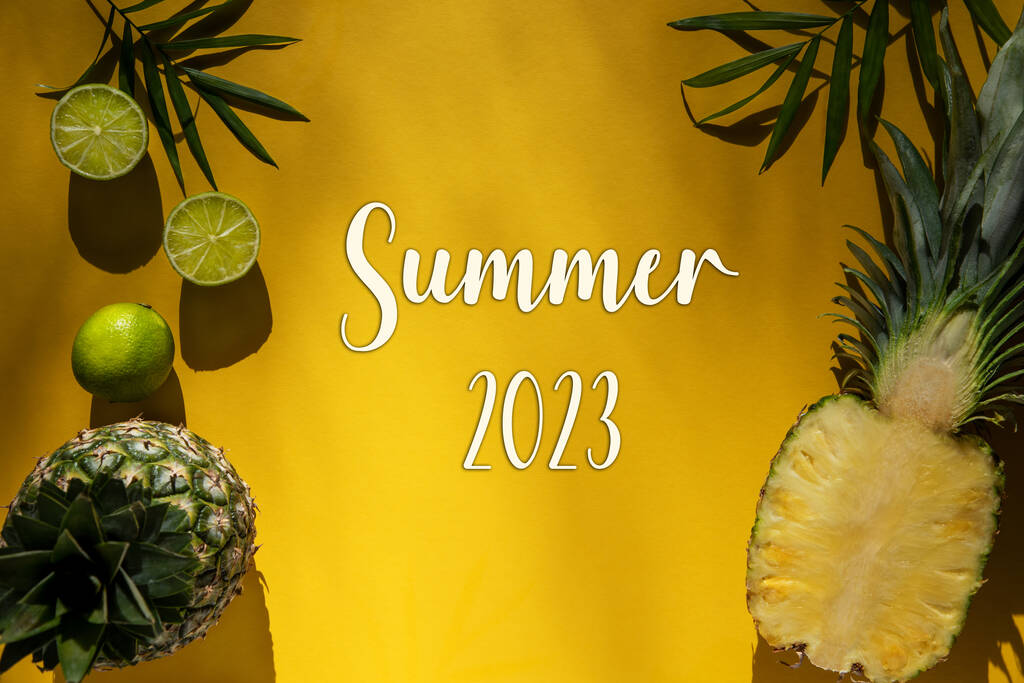 Yellow Flat Lay z angielskim tekstem Lato 2023. Żółte letnie tło z tropikalnych owoców, takich jak cytryna i ananas i liść palmowy. - Zdjęcie, obraz