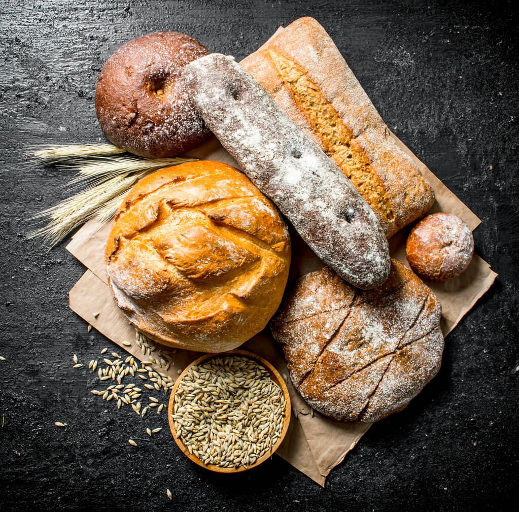 La gamma di diversi tipi di pane dalla segale e farina di grano. Su sfondo nero rustico
 - Foto, immagini