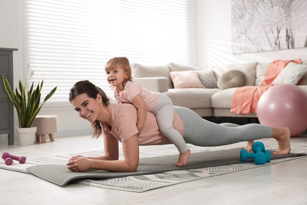 Mère faisant de l'exercice avec sa fille à la maison - Photo, image