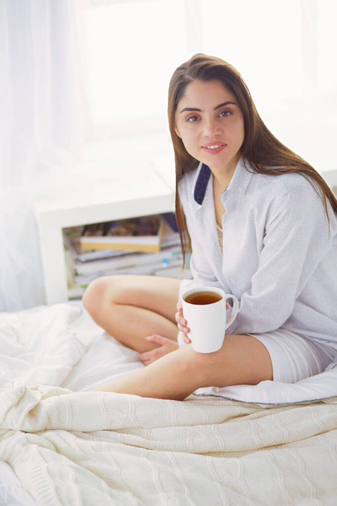 Woman sitting in bed reading a book and having breakfast. - Photo, Image