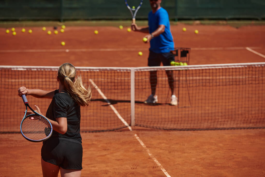 Una tenista profesional y su entrenador entrenando en un día soleado en la cancha de tenis. Formación y preparación de un tenista profesional. - Foto, imagen