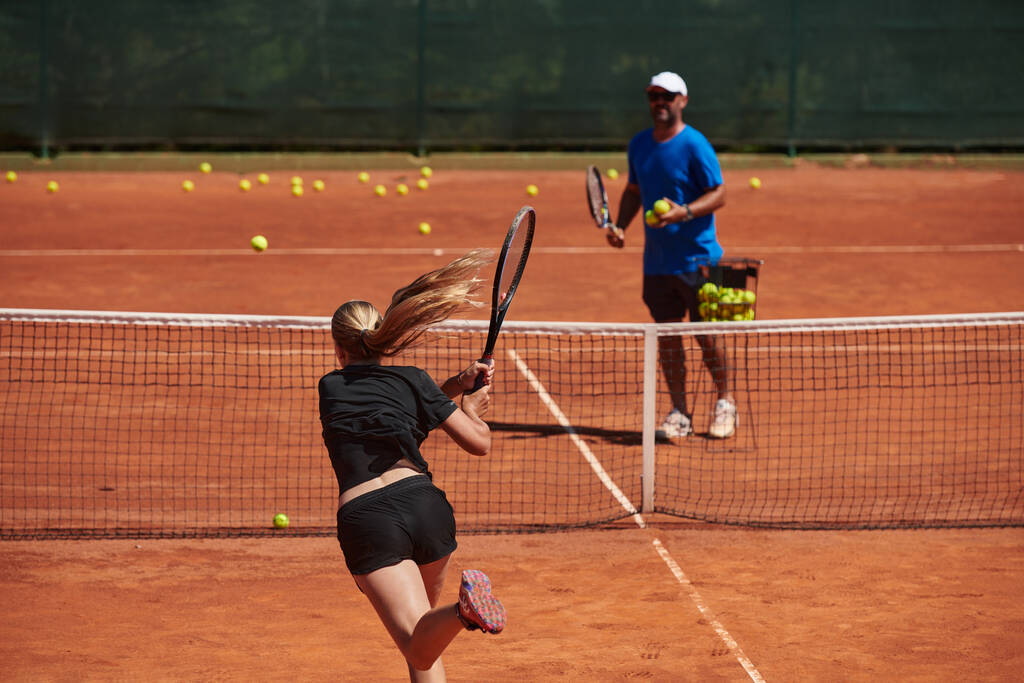 Eine professionelle Tennisspielerin und ihr Trainer beim Training an einem sonnigen Tag auf dem Tennisplatz. Ausbildung und Vorbereitung eines professionellen Tennisspielers. - Foto, Bild