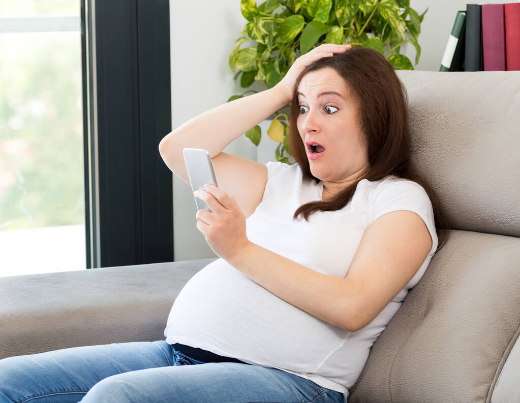 Tiro de uma mulher grávida espantada com promoção on-line em casa - Foto, Imagem