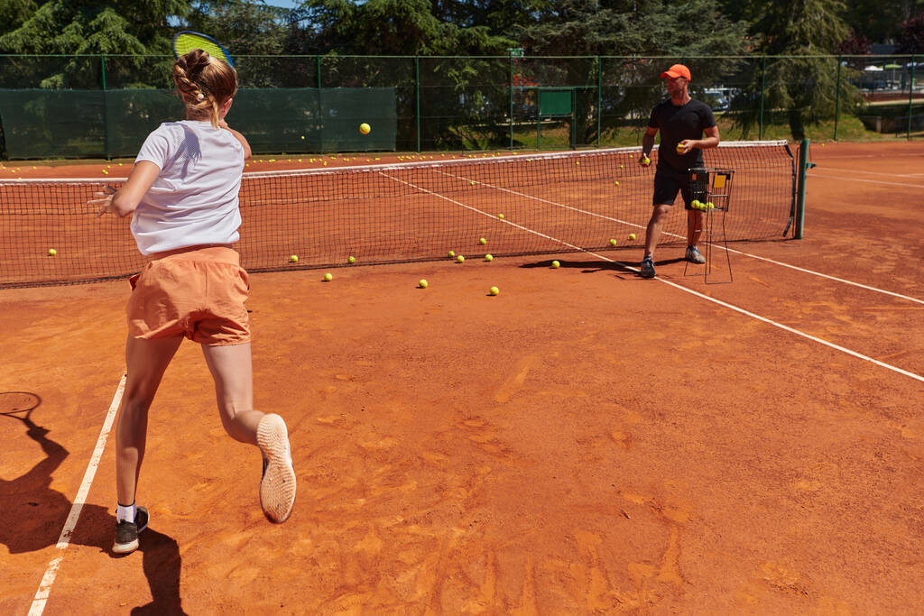Egy profi teniszező és edzője edz egy napsütéses napon a teniszpályán. A hivatásos teniszező képzése és felkészítése. - Fotó, kép