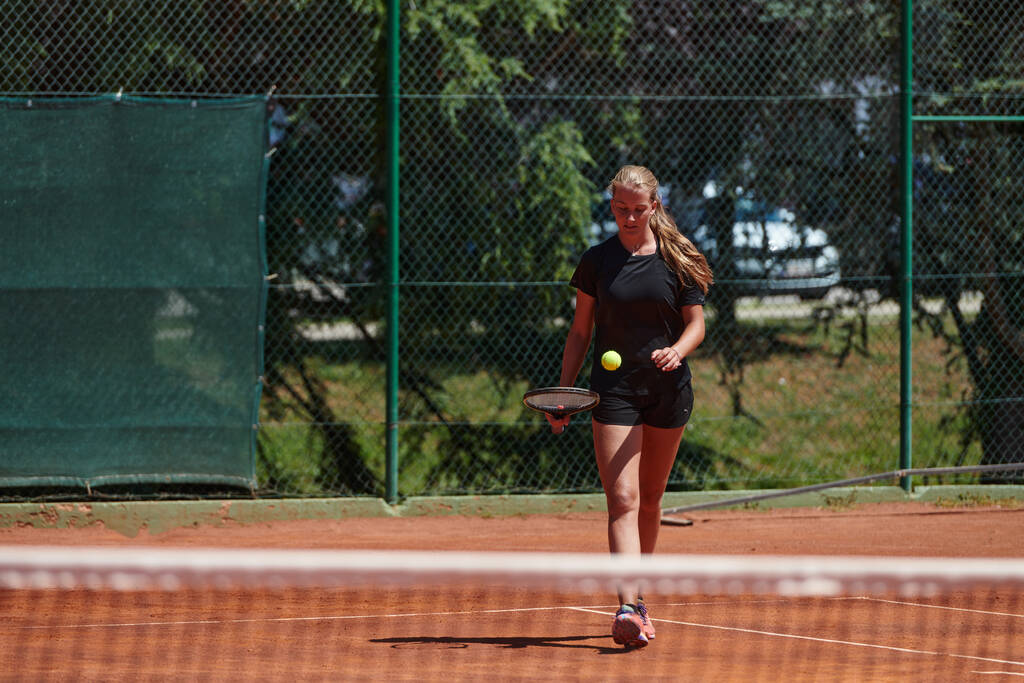Una joven que muestra habilidades profesionales de tenis en un partido competitivo en un día soleado, rodeada por la estética moderna de una cancha de tenis - Foto, Imagen