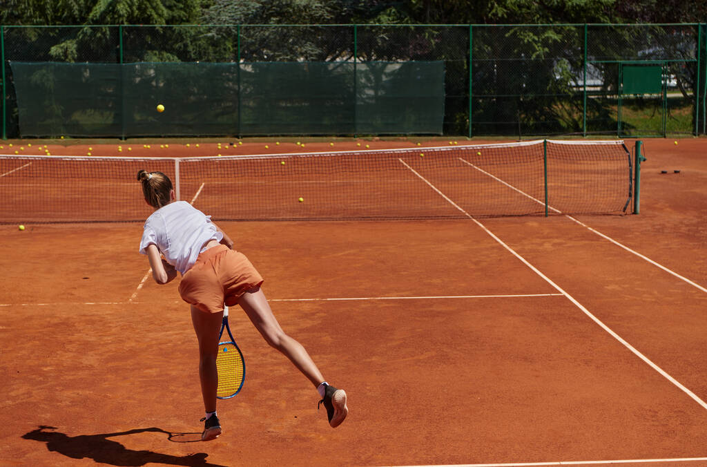 Tenis oyuncusu dikkatle odaklanarak, tenis kortuna yaptığı servisi hassasiyetle ve kararlılıkla mükemmelleştiriyor ve yeteneklerini geliştirmeye olan bağlılığını gösteriyor. - Fotoğraf, Görsel