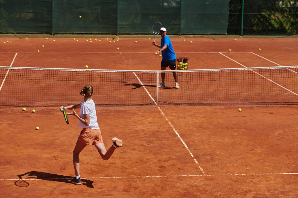Профессиональная теннисистка и ее тренер тренируются в солнечный день на теннисном корте. Обучение и подготовка профессионального теннисиста. - Фото, изображение