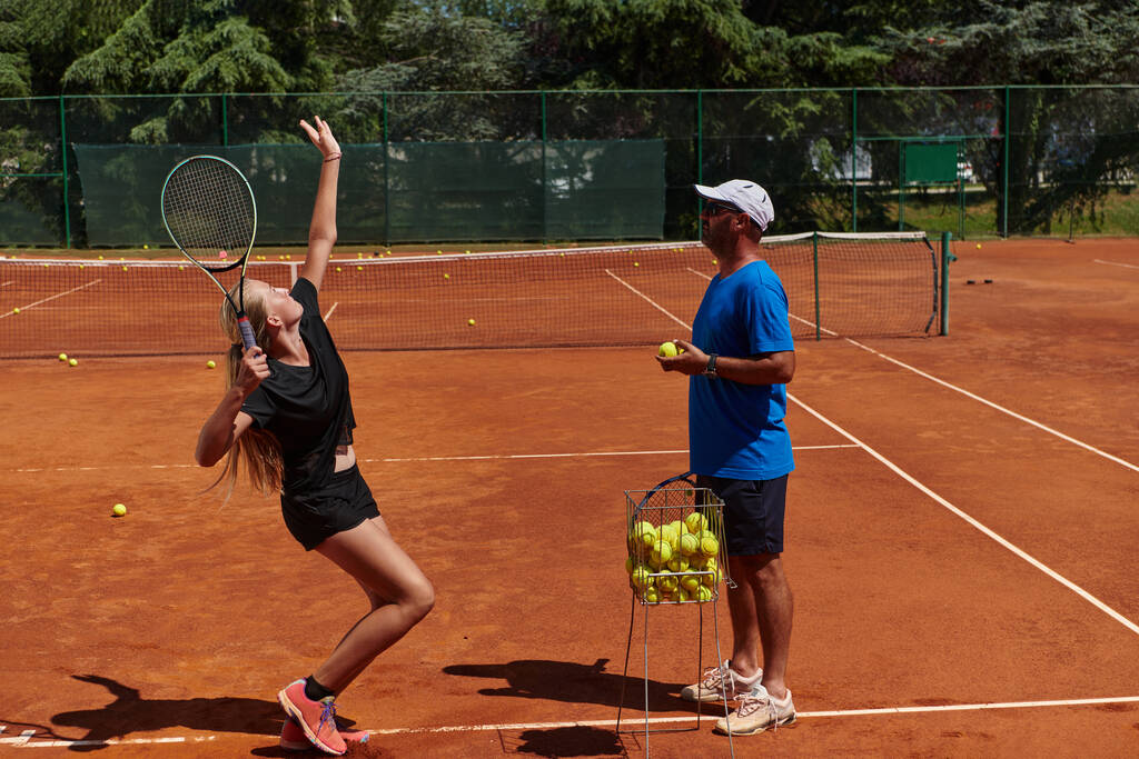 Μια επαγγελματίας τενίστρια και ο προπονητής της προπονούνται μια ηλιόλουστη μέρα στο γήπεδο του τένις. Κατάρτιση και προετοιμασία ενός επαγγελματία τενίστα. - Φωτογραφία, εικόνα