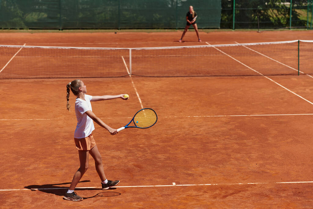 Chicas jóvenes en un animado partido de tenis en un día soleado, demostrando sus habilidades y entusiasmo en una pista de tenis moderna - Foto, imagen