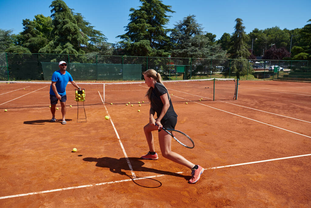 A professional tennis player and her coach training on a sunny day at the tennis court. Training and preparation of a professional tennis player. - Photo, Image