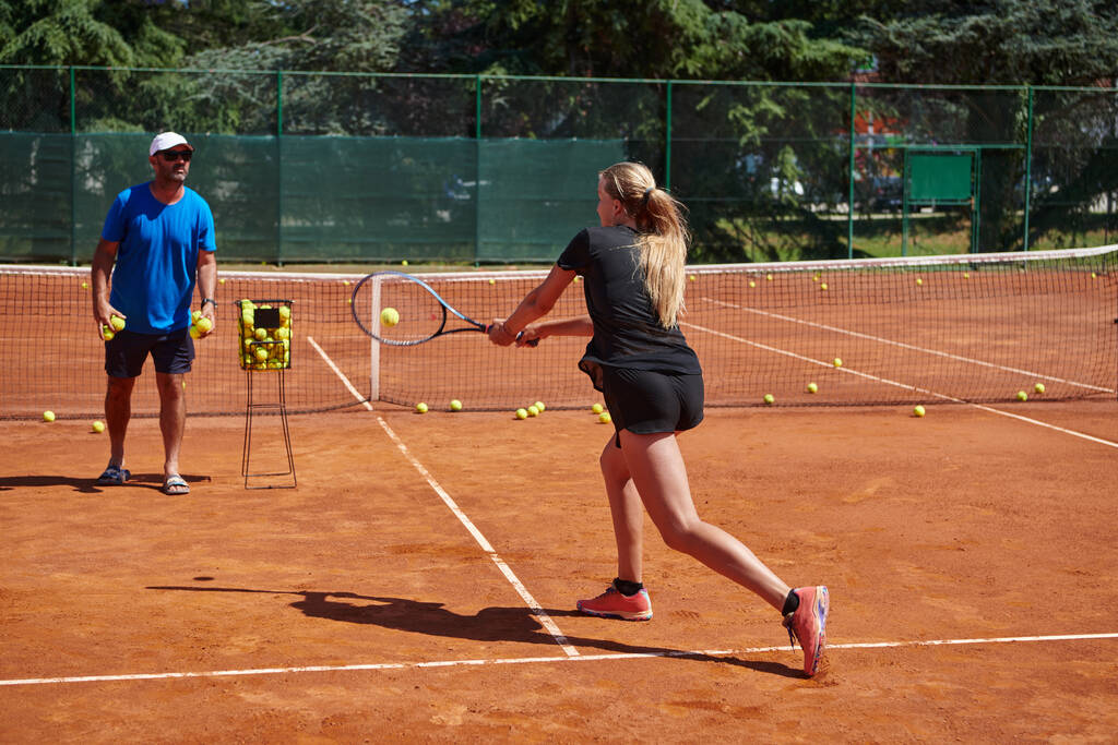 Een professionele tennisspeelster en haar coach trainen op een zonnige dag op de tennisbaan. Training en voorbereiding van een professionele tennisspeler. - Foto, afbeelding