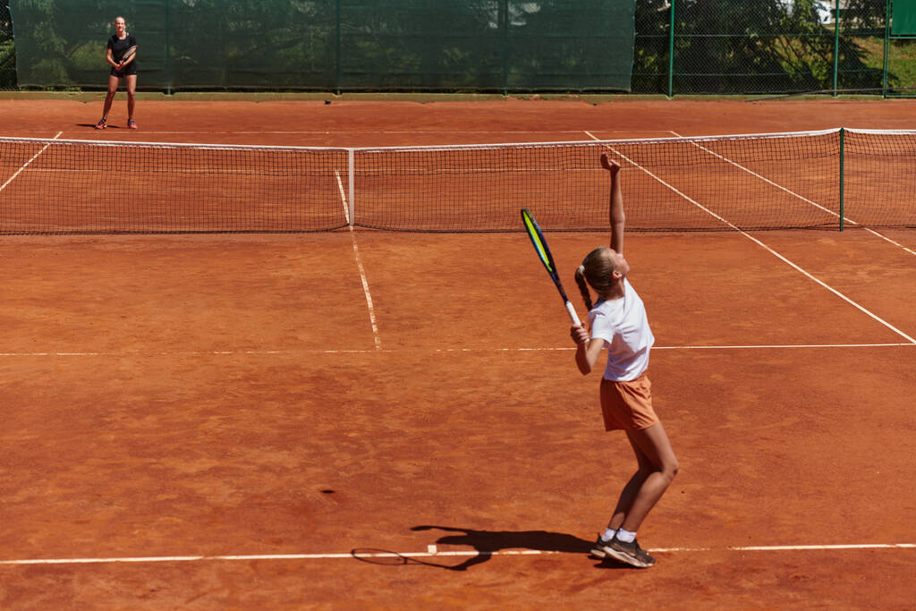 Genç kızlar güneşli bir günde canlı bir tenis maçında modern bir tenis kortunda yeteneklerini ve heveslerini gösteriyorlar. - Fotoğraf, Görsel