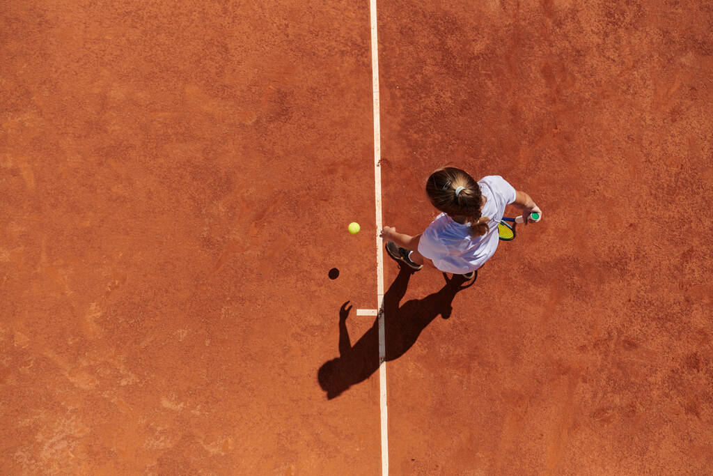 Κάτοψη του μια επαγγελματική γυναίκα τενίστρια σερβίρει την μπάλα του τένις στο γήπεδο με ακρίβεια και δύναμη.  - Φωτογραφία, εικόνα