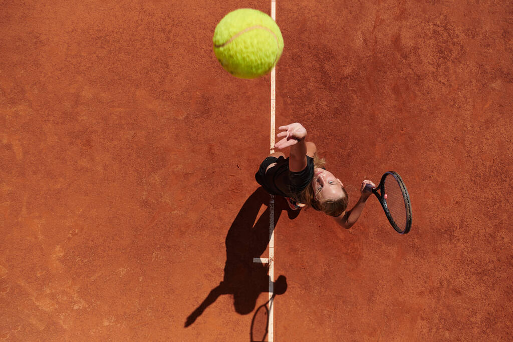 Profesyonel bir bayan tenisçinin üst görüntüsü tenis topunu sahada hassas ve güçlü bir şekilde servis eder..  - Fotoğraf, Görsel